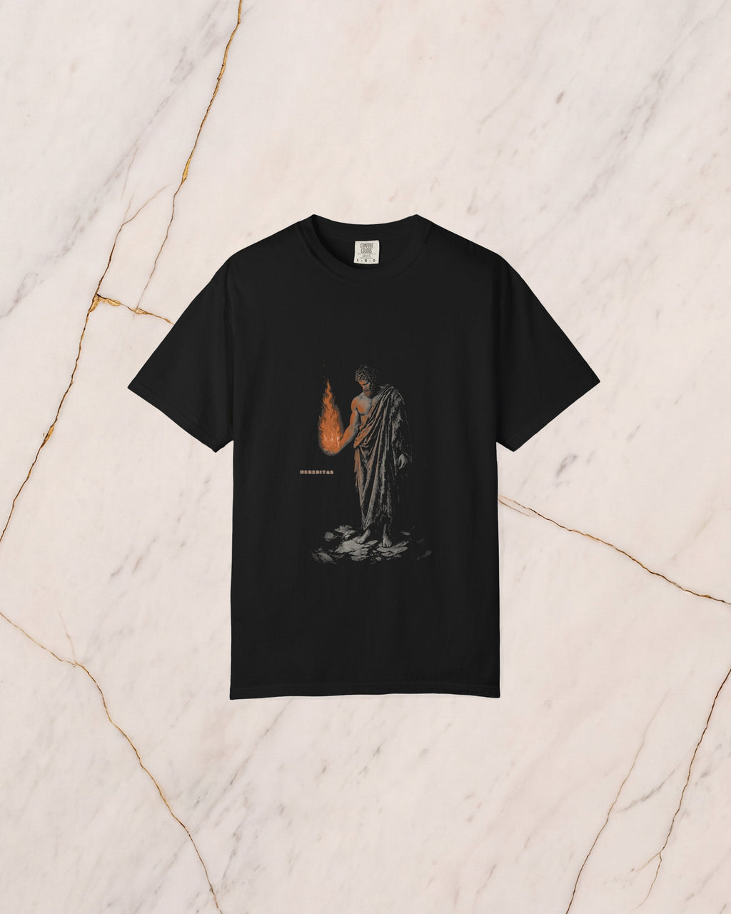 The PROMETHEUS shirt in black, laid on pale marble. Prometheus holds the stolen fire in his open hand, and its light falls on his forearm, his chest and the underside of his beard.