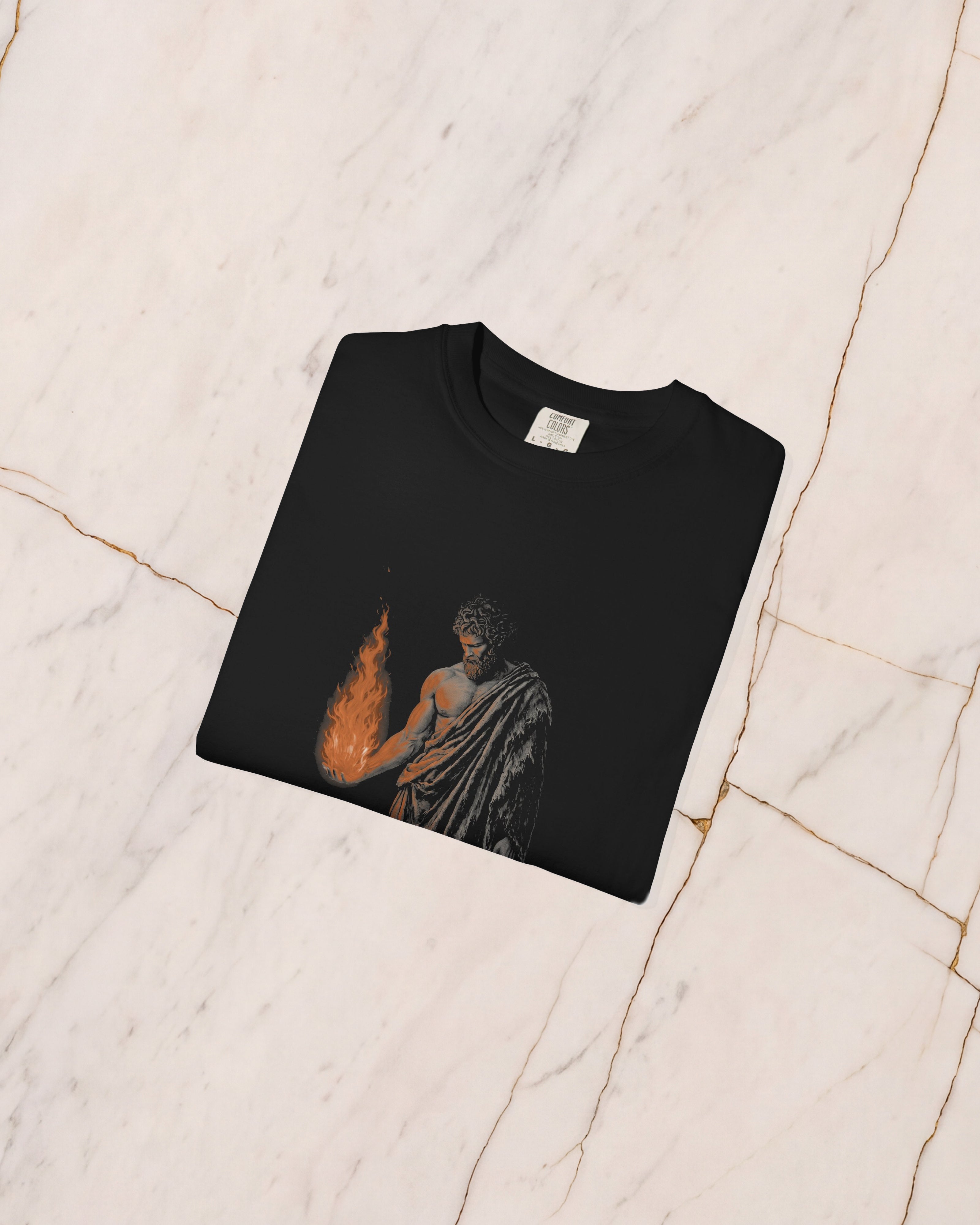 The PROMETHEUS shirt in black, folded on pale marble, showing the weight of the cotton and the detail of the artwork.