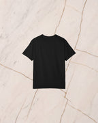 The back of the PROMETHEUS shirt, plain black, laid on pale marble.