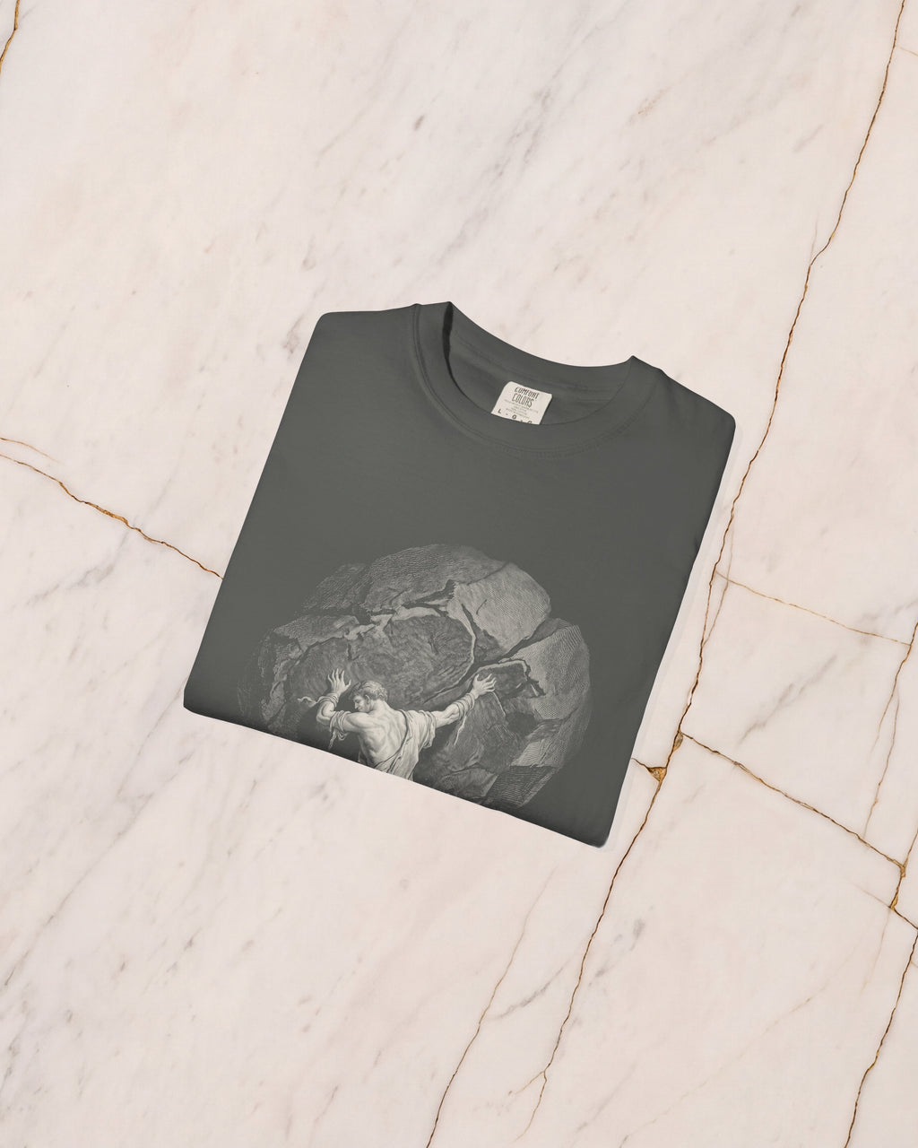 The SISYPHUS shirt in pepper folded on pale marble, showing the weight of the cotton and the detail of the artwork.