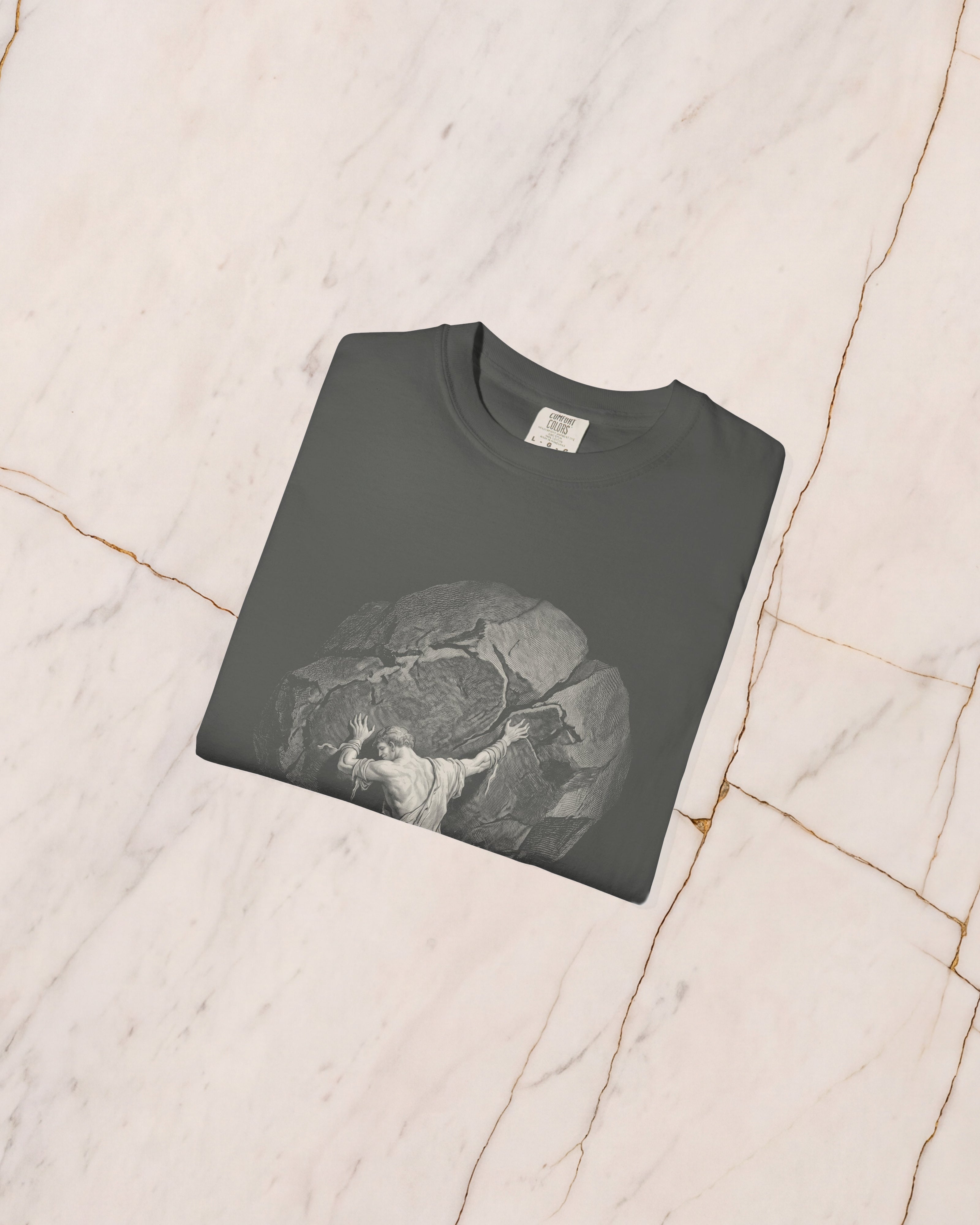 The SISYPHUS shirt in pepper folded on pale marble, showing the weight of the cotton and the detail of the artwork.