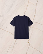 The back of the THESEUS t-shirt in True Navy, unprinted, laid flat on pale marble.