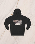 The VENATOR hoodie in black, laid flat on pale marble. A hunter and a lion alone on the arena sand, the temples of the city rising beyond the wall, drawn in bone line and lit by a low sun.