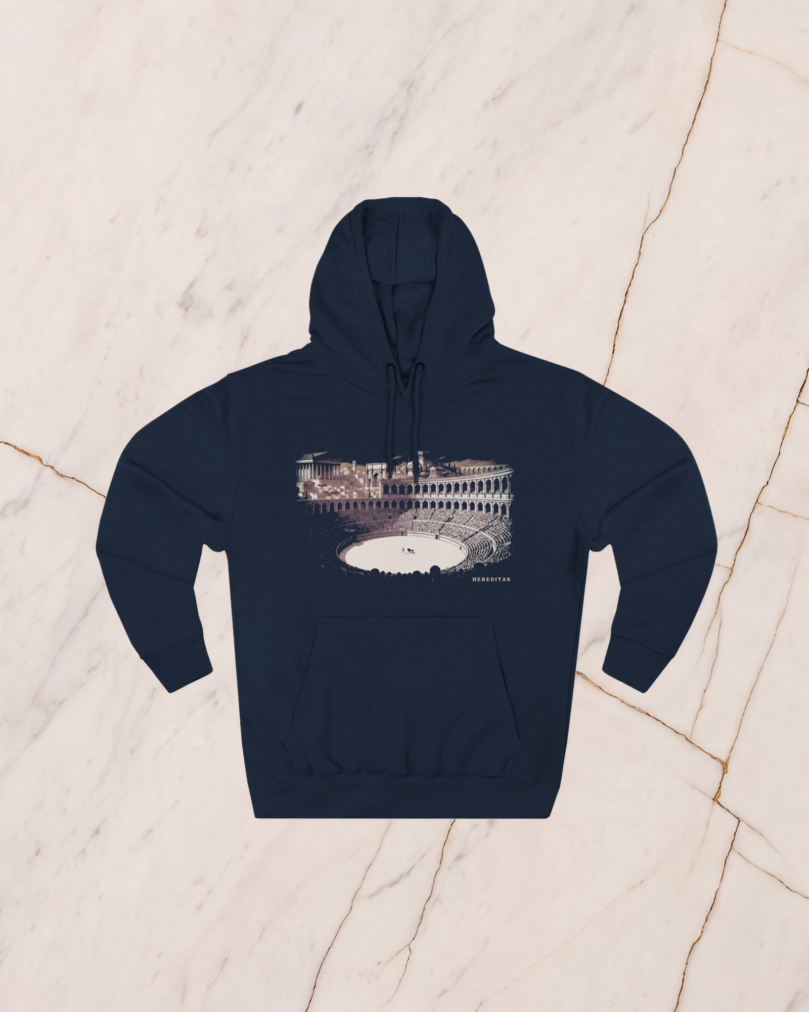 The VENATOR hoodie in navy, laid flat on pale marble. A hunter and a lion alone on the arena sand, the temples of the city rising beyond the wall, drawn in bone line and lit by a low sun.
